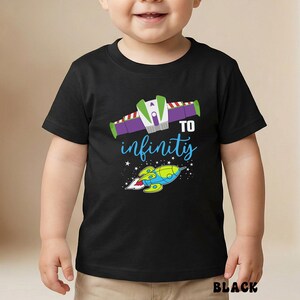 May include: Black t-shirt featuring a colorful graphic design with a spaceship and the words "TO infinity". The design includes a green, purple, and white spaceship and a blue and yellow rocket. The shirt is for children.