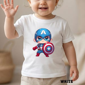 Op de afbeelding: Wit T-shirt met korte mouwen met een cartoon illustratie van Captain America. Het personage draagt een blauw en rood kostuum en houdt een schild met een ster vast. Het woord "WHITE" staat onderaan.