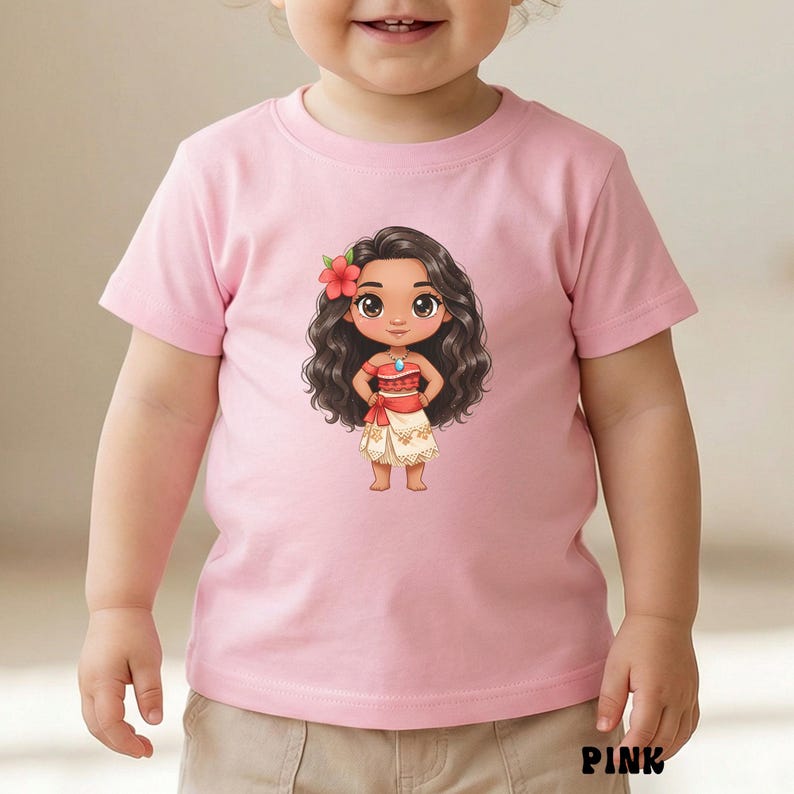 May include: A light pink t-shirt featuring a cartoon illustration of a character with long, dark curly hair, a red flower, and a red and white outfit. The character has large eyes and a turquoise necklace. The word "PINK" is printed at the bottom.