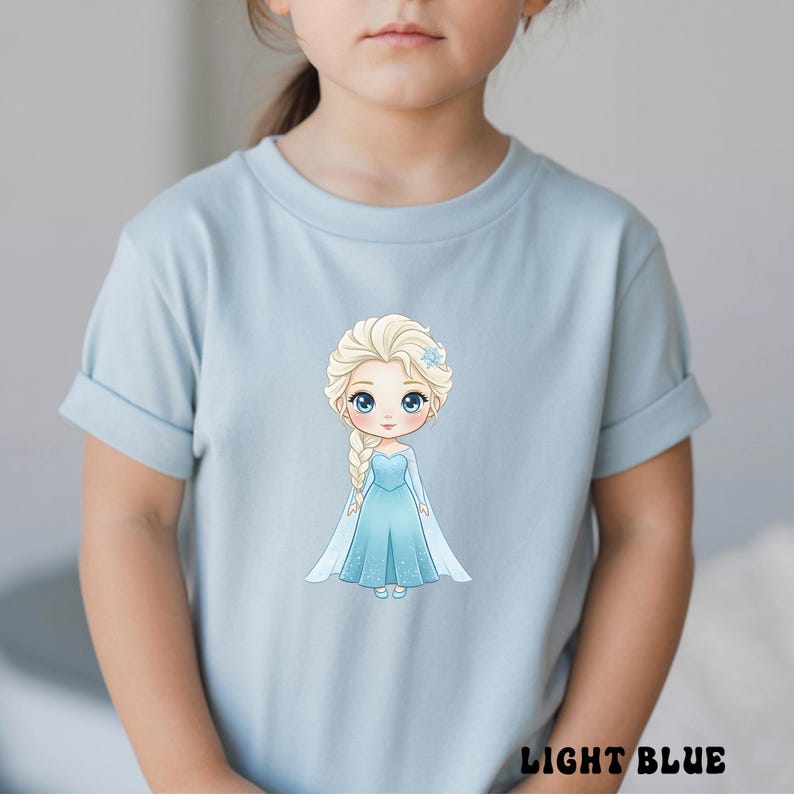 Puede incluir: Camiseta azul claro con una ilustraci&oacute;n de dibujos animados de una princesa con un vestido azul, una trenza larga y una flor azul en el pelo. El texto "LIGHT BLUE" est&aacute; en la parte inferior.