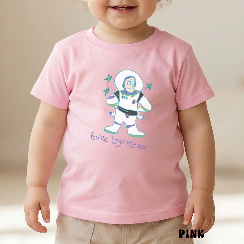 May include: Pink short-sleeved t-shirt featuring a cartoon illustration of Buzz Lightyear with the text "Buzz Lightyear" in a light blue color. The design includes stars and the word "PINK" at the bottom.
