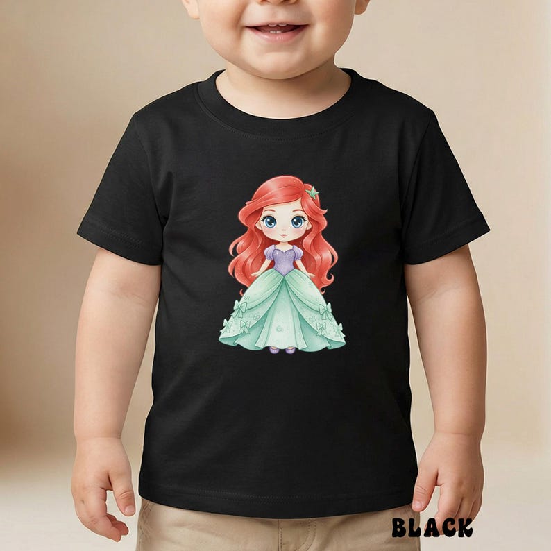 Puede incluir: Una camiseta negra de manga corta con una ilustraci&oacute;n gr&aacute;fica central de un personaje de dibujos animados con largo cabello rojo, que viste un corpi&ntilde;o morado y un voluminoso vestido verde claro adornado con lazos y un accesorio de estrella.