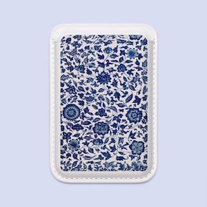 May include: A rectangular adhesive card holder featuring a white background with a dense, intricate pattern of dark blue flowers, leaves, and vines. The accessory has a clean white border with visible stitching along the outer edges.
