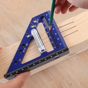 Puede incluir: Escuadra de velocidad de aluminio azul con marcas de medición y ángulos en grados. Se utiliza un lápiz para marcar una tabla de madera. La escuadra tiene medidas en centímetros y se utiliza para carpintería.