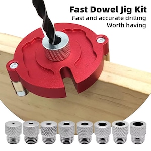 Puede incluir: Un kit rojo de plantilla de espiga rápida con una broca negra insertada en una tabla de madera. El kit incluye un juego de casquillos guía de perforación plateados. El texto en la imagen dice "Fast Dowel Jig Kit" y "Fast and accurate drilling Worth having."