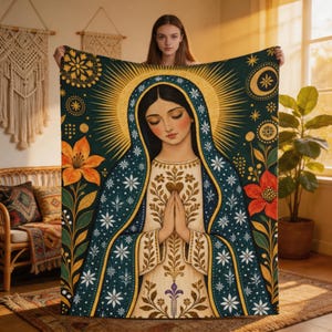 May include: A rectangular throw blanket featuring a central illustration of a figure with hands pressed together in prayer. The design includes a dark teal cloak with white floral patterns, a gold halo, and orange and red flowers on the sides.
