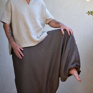 A person wearing a light brown linen top with a v-neck and a brown linen pair of harem pants.
