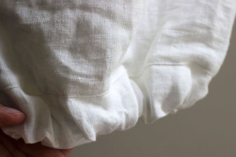 May include: White linen fabric with a gathered edge. The fabric is soft and textured.