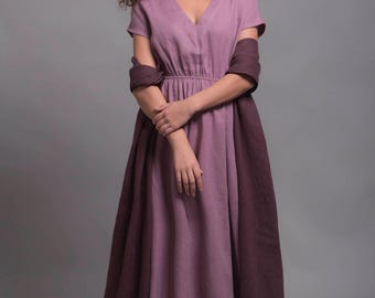 May include: A long, flowing dress in shades of mauve and plum. The dress features a V-neckline and short sleeves, with a matching shawl draped over the shoulders. The dress is made of a soft, flowing fabric, perfect for a casual or formal occasion.