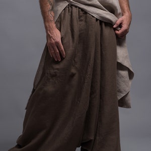 A person wearing brown linen sarousel with a loose, flowing fit. The pants have a wide leg and a gathered waist.