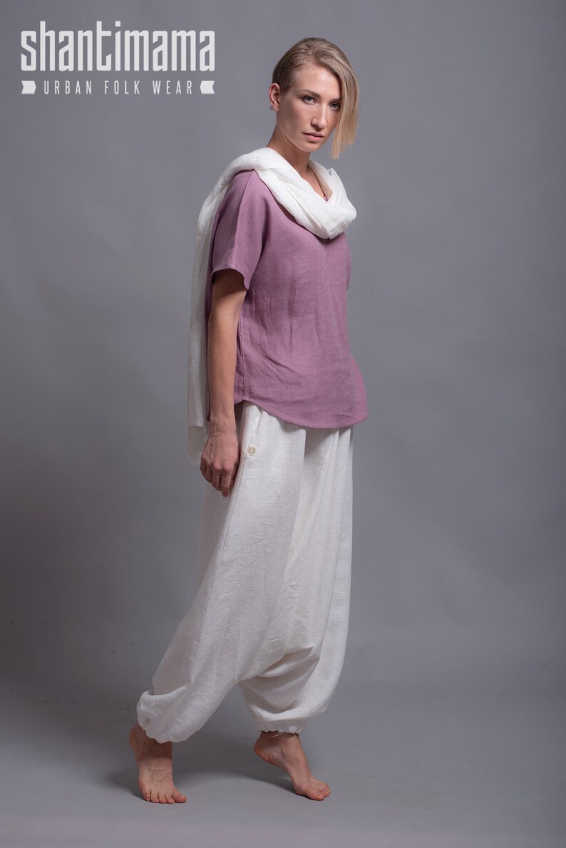 May include: A woman wearing a mauve linen top with a white linen scarf and white linen pants. The pants have a loose, wide-leg style. The text "shantimama URBAN FOLK WEAR" is visible at the top of the image.