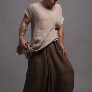 A person wearing a light brown linen top with a loose fit and brown linen pants with a wide leg.