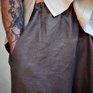 A pair of brown linen trousers with a relaxed fit. The pants have side 
pockets and a wide leg.