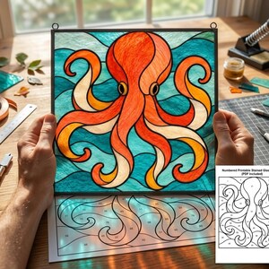 May include: A square stained glass panel featuring a vibrant orange octopus with eight tentacles against a wavy teal and blue background. The piece is held up, revealing a numbered paper pattern template underneath and a small reference card.