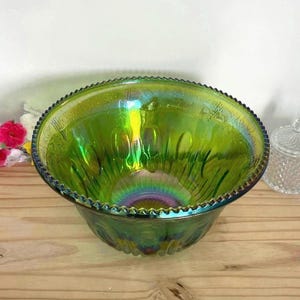 Peut inclure: Un grand bol en verre carnaval vert irisé, de forme ronde, doté d'un bord festonné et dentelé. L'intérieur présente un éclat réfléchissant multicolore avec un motif pressé de côtes verticales et des motifs floraux en relief sur le bord.