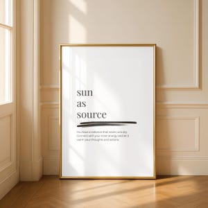 Op de afbeelding: Een ingelijste kunstdruk met een gouden rand. De witte achtergrond toont de woorden "sun as source" in een minimalistisch lettertype, met een zwarte lijn eronder. Hieronder staat een citaat over innerlijke energie.