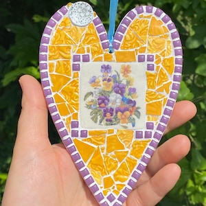 Mosaico de cerámica amarilla rota hecho a mano con forma de corazón y flores de pensamiento. Regalo para el Día de la Madre.
