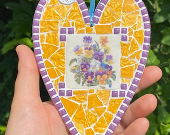 Mosaico de cerámica amarilla rota hecho a mano con forma de corazón y flores de pensamiento. Regalo para el Día de la Madre.