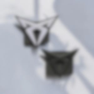 以下が含まれることがあります： スタイリッシュな幾何学模様の抽象的なダークグレーのオブジェクトが2つ。オブジェクトは、尖った上端と中央のひし形の開口部を備えた対称的な形状をしています。背景は柔らかく、明るいグレーです。