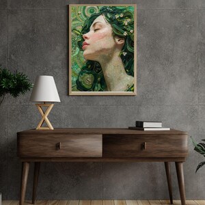 Puede incluir: Una impresión artística enmarcada que presenta a una mujer con los ojos cerrados y cabello verde adornado con pequeñas flores blancas. La obra de arte tiene una textura de mosaico y un fondo verde y dorado. La impresión se exhibe en una consola de madera oscura.