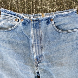 May include: A pair of light blue denim jeans with a frayed hem and a zipper detail on the side seams.