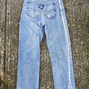 May include: Light blue denim jeans with a heart-shaped patch on the back pocket and a zipper detail on the side seam.