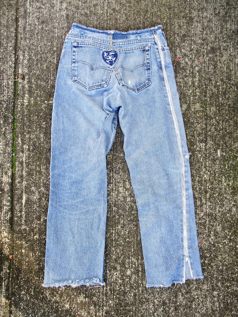 May include: Light blue denim jeans with a heart-shaped patch on the back pocket and a zipper detail on the side seam.
