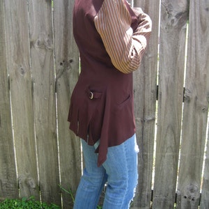 May include: A maroon jacket with a brown and white striped sleeve. The jacket has a belt and a long, flowing tail.