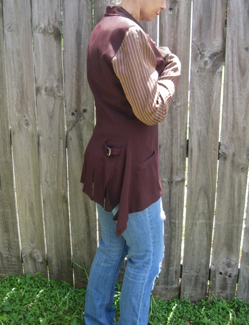 May include: A maroon jacket with a brown and white striped sleeve. The jacket has a belt and a long, flowing tail.