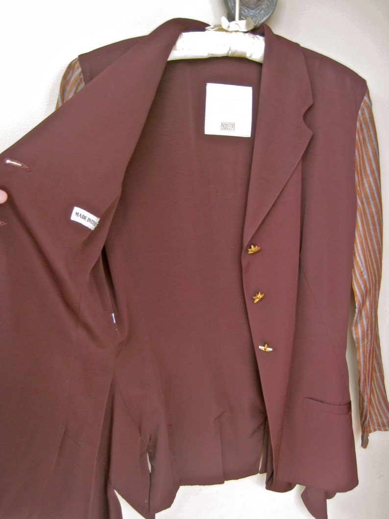 May include: A maroon blazer with gold buttons and a striped lining. The blazer has a label that says "Made in Italy" and another label that says "Roberto Cavalli".