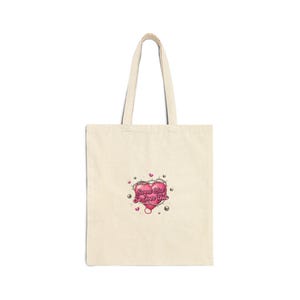 Può includere: Borsa tote color crema con un cuore rosa. Il cuore è trafitto da spine e presenta la scritta "Sweet But So Over You". La borsa ha due manici ed è realizzata in tela.