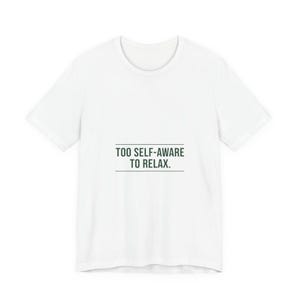 May include: White t-shirt with the text "TOO SELF-AWARE TO RELAX" in a dark green font. The text is centered on the front of the shirt, with a horizontal line beneath the text. The shirt has short sleeves and a crew neck.