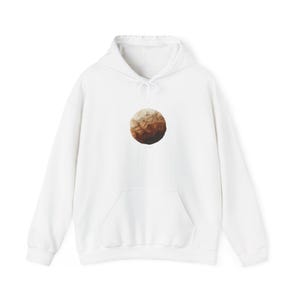May include: White hooded sweatshirt with a front pocket and a drawstring. The sweatshirt features a circular graphic in shades of brown and beige, resembling a planet or abstract design.