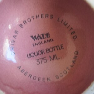 May include: A close-up of the base of a pink liquor bottle. The text on the bottle reads "CHIVAS BROTHERS LIMITED. WADE ENGLAND. LIQUOR BOTTLE 375 ML. ABERDEEN SCOTLAND."