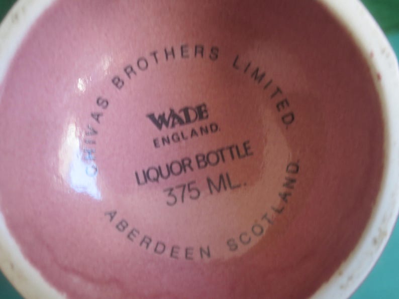 May include: A close-up of the base of a pink liquor bottle. The text on the bottle reads "CHIVAS BROTHERS LIMITED. WADE ENGLAND. LIQUOR BOTTLE 375 ML. ABERDEEN SCOTLAND."