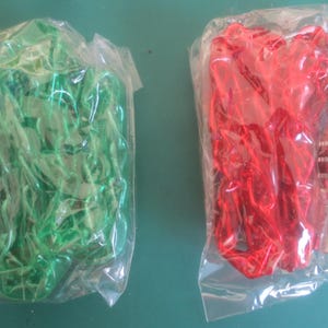 Puede incluir: Dos juegos de art&iacute;culos decorativos, cada uno en una bolsa de pl&aacute;stico transparente. Un juego es verde, el otro es rojo. Cada juego incluye un tap&oacute;n de botella de color plateado. El juego verde tiene un elemento decorativo, mientras que el rojo tiene una cinta.