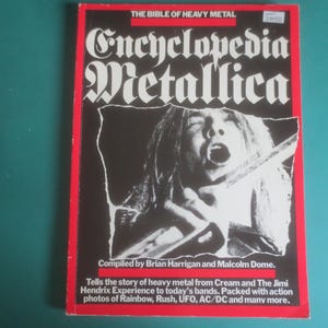 May include: A paperback book titled Encyclopedia Metallica, The Bible of Heavy Metal, compiled by Brian Harrigan and Malcolm Dome. The black cover features a white graphic of a person singing, with red borders and white text detailing the contents.