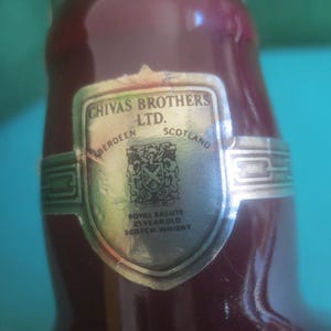 May include: Close-up of a burgundy-colored bottle with a silver label. The label reads "Chivas Brothers Ltd. Aberdeen Scotland" and features a crest. The bottle is labeled "Royal Salute 21 Year Old Scotch Whisky."