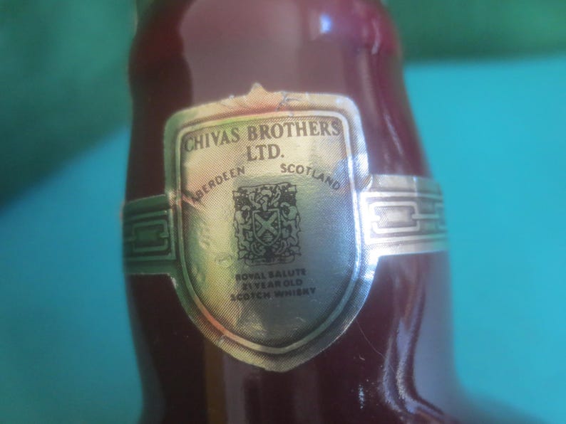 May include: Close-up of a burgundy-colored bottle with a silver label. The label reads "Chivas Brothers Ltd. Aberdeen Scotland" and features a crest. The bottle is labeled "Royal Salute 21 Year Old Scotch Whisky."