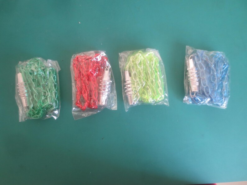 Puede incluir: Cuatro cadenas de colores en envases de pl&aacute;stico. Las cadenas son verdes, rojas, verde lima y azules. Cada cadena tiene un cierre met&aacute;lico plateado. Los art&iacute;culos se muestran sobre una superficie verde.