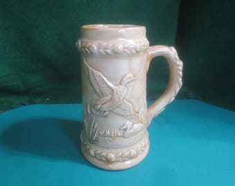 Jarra de cerveza de cerámica con diseño en relieve de patos ánade real en un pantano, de mediados de siglo (1975).
