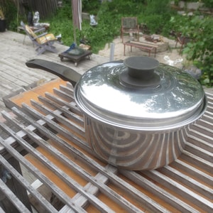 Peut inclure: Une casserole en acier inoxydable avec une finition polie, dotée d'un long manche noir et d'un couvercle assorti en acier inoxydable avec un bouton central noir. La marmite a un corps cylindrique et une base plate pour la cuisson.