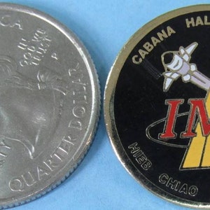 May include: A gold-colored coin with a black background featuring a space shuttle, two yellow lines, and the text "CABANA HALSELL WALZ IML CHIAO THOMAS MUKAI".