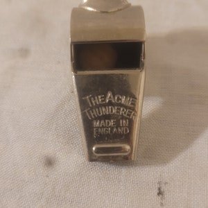 May include: A silver whistle with the words "The Acme Thunderer Made in England" engraved on the side.