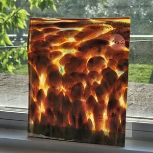May include: A rectangular glass panel featuring a swirling pattern of amber, brown, and golden yellow tones resembling flames. The surface has handwritten text reading 8x6.5 Rolled Edge Vintage Fire Puffs B S248 and a circular sticker with 8x6.5.