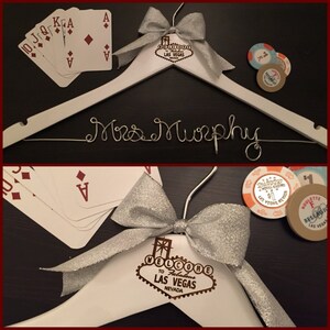 May include: White wooden hanger with a silver bow and a gold Las Vegas sign with the text "Welcome to Fabulous Las Vegas, Nevada". The hanger has the name "Mrs. Murphy" written in silver wire.