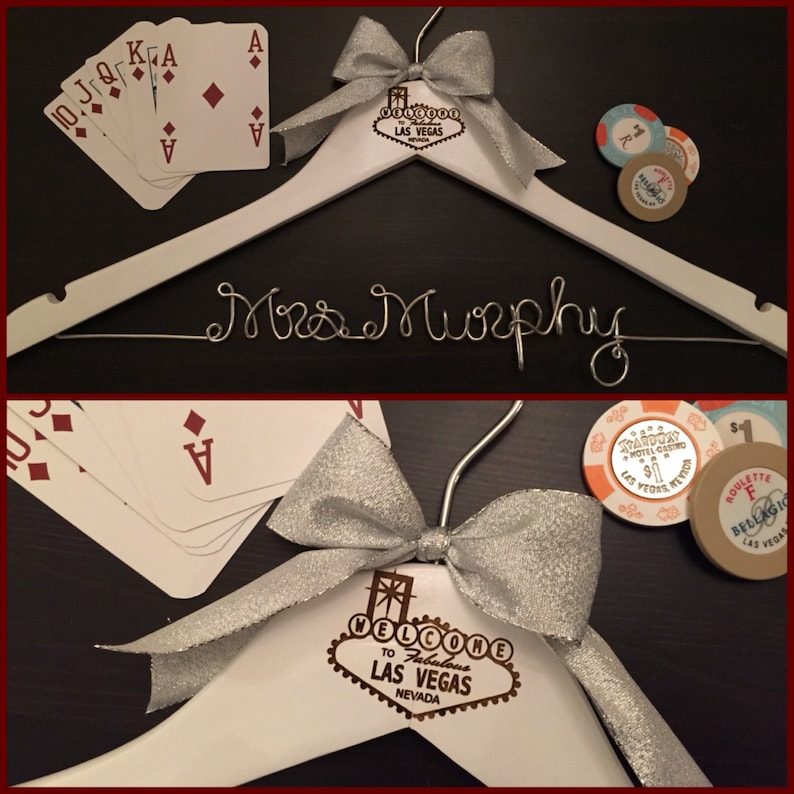 May include: White wooden hanger with a silver bow and a gold Las Vegas sign with the text "Welcome to Fabulous Las Vegas, Nevada". The hanger has the name "Mrs. Murphy" written in silver wire.