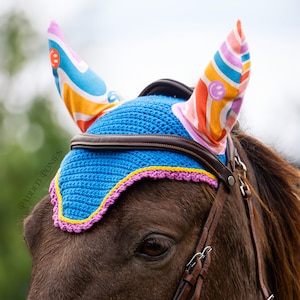 May include: A blue crocheted horse fly bonnet with pink and yellow trim and colorful fabric ear covers with a smiley face design. The ear covers have a rainbow swirl pattern.