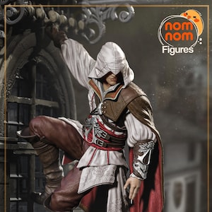 May include: A detailed action figure of a character in a white hooded tunic, brown leather accents, and red cape, climbing a stone structure. The figure has a determined expression and is posed mid-climb. The figure is from the "nom nom Figures" brand.