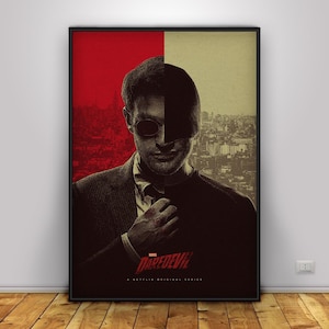 May include: A framed poster featuring a split background of red and beige, with a portrait of a man wearing sunglasses. The poster has the title "DAREDEVIL" and the text "A NETFLIX ORIGINAL SERIES" at the bottom.